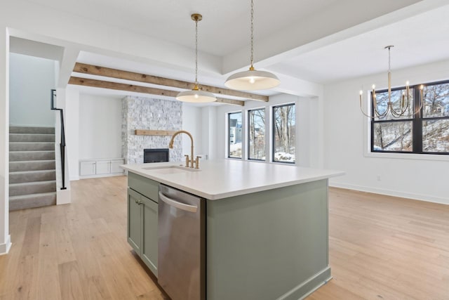 kitchen featuring light wood-style flooring, a kitchen island with sink, a sink, light countertops, and stainless steel dishwasher