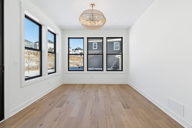 spare room featuring light wood-style floors, visible vents, and baseboards