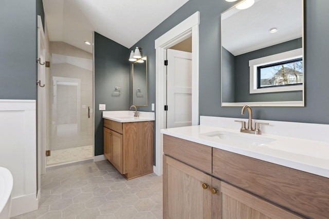 bathroom with lofted ceiling, a shower stall, two vanities, and a sink