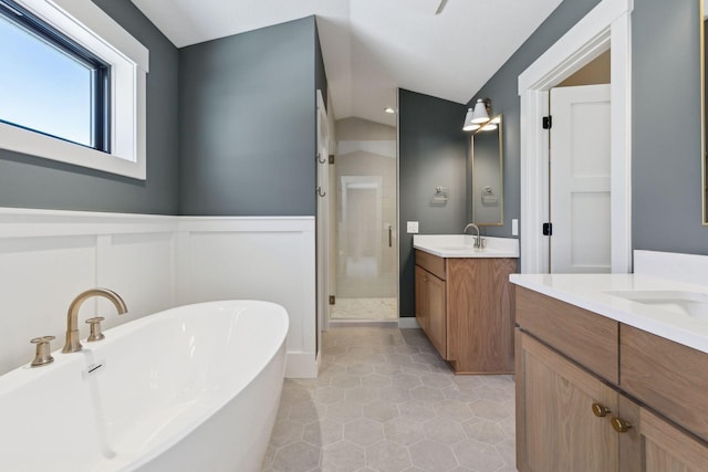 bathroom with a wainscoted wall, a soaking tub, two vanities, a sink, and a shower stall