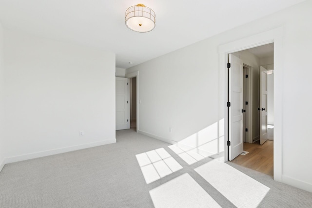 empty room with light colored carpet and baseboards