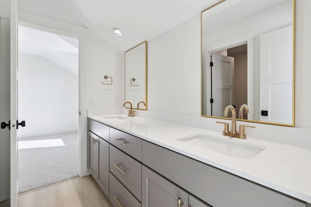 full bath with lofted ceiling, wood finished floors, a sink, and double vanity