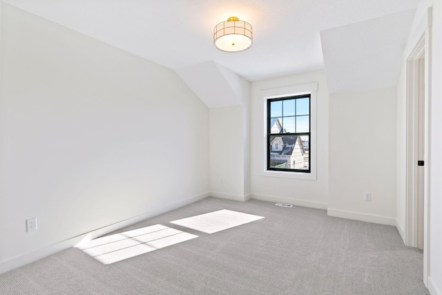 spare room with light carpet, lofted ceiling, and baseboards