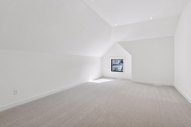 additional living space with light carpet, baseboards, and vaulted ceiling