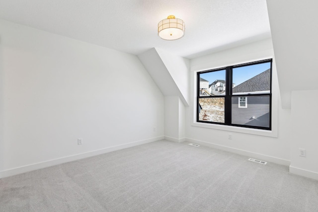 bonus room with light colored carpet, visible vents, lofted ceiling, and baseboards