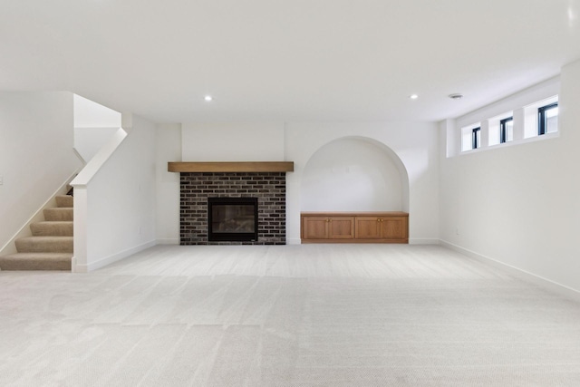 unfurnished living room featuring light carpet, baseboards, stairway, a fireplace, and recessed lighting