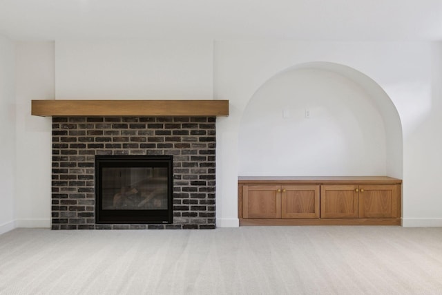 unfurnished living room with light carpet, a brick fireplace, and baseboards