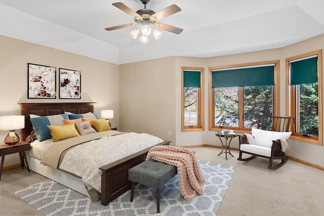 bedroom with light carpet, a raised ceiling, and ceiling fan