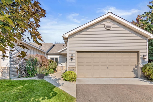 single story home with a garage, driveway, a front lawn, and brick siding