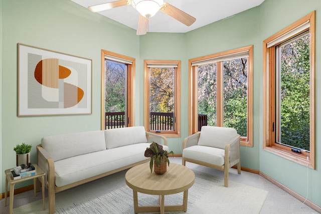 living area featuring light carpet, baseboards, and a ceiling fan