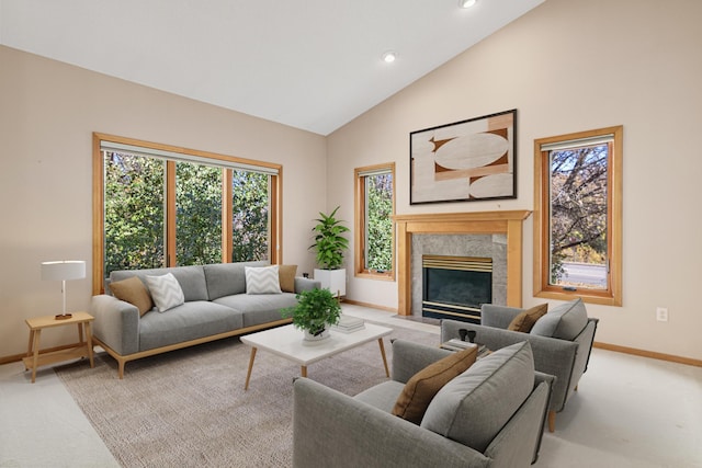 carpeted living area with a high end fireplace, a healthy amount of sunlight, high vaulted ceiling, and baseboards