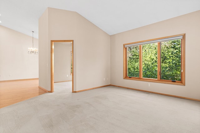 carpeted spare room with baseboards, an inviting chandelier, and vaulted ceiling