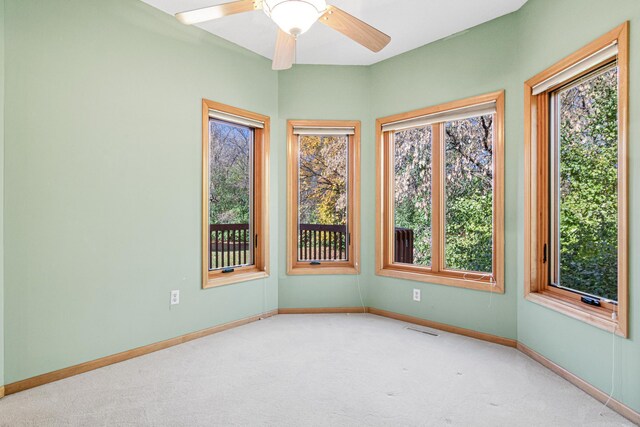 carpeted empty room featuring visible vents, a ceiling fan, and baseboards