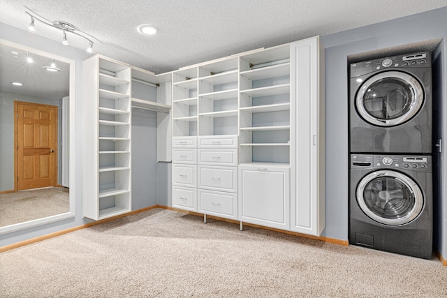 washroom featuring baseboards, laundry area, a textured ceiling, stacked washer / dryer, and carpet flooring