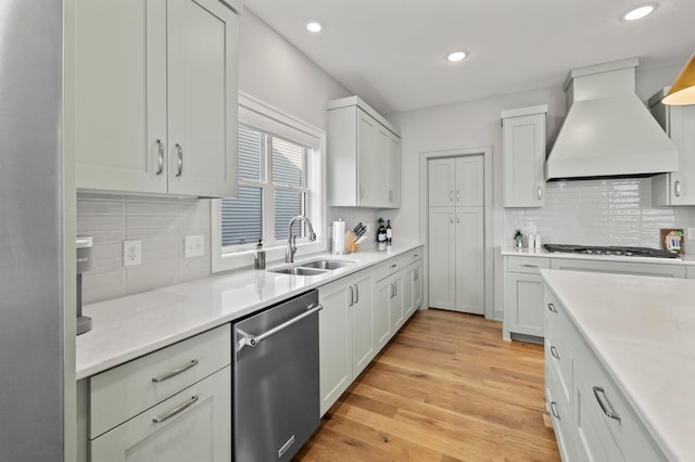 kitchen with sink, stainless steel appliances, light hardwood / wood-style flooring, premium range hood, and white cabinets