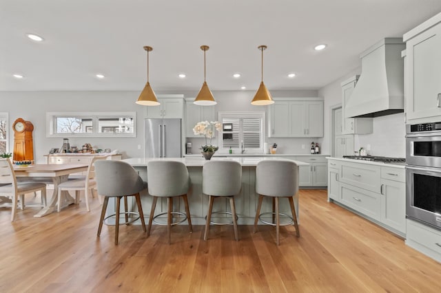 kitchen with appliances with stainless steel finishes, premium range hood, tasteful backsplash, pendant lighting, and a center island