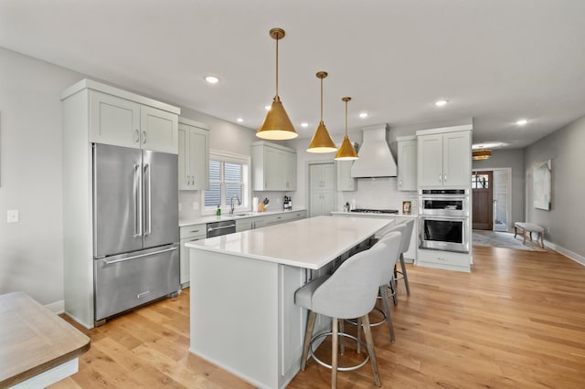 kitchen featuring decorative backsplash, custom exhaust hood, stainless steel appliances, pendant lighting, and a center island