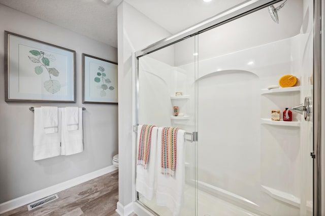 bathroom featuring walk in shower, hardwood / wood-style flooring, and toilet