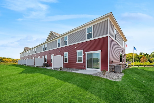 rear view of property with central AC unit and a yard