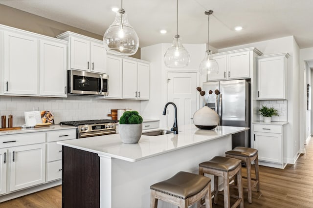 kitchen with pendant lighting, white cabinets, a kitchen island with sink, and appliances with stainless steel finishes