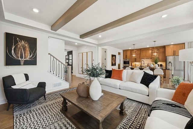 living room featuring beam ceiling and sink