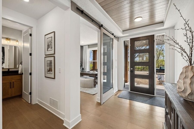 entryway with hardwood / wood-style flooring, a barn door, a healthy amount of sunlight, and wood ceiling