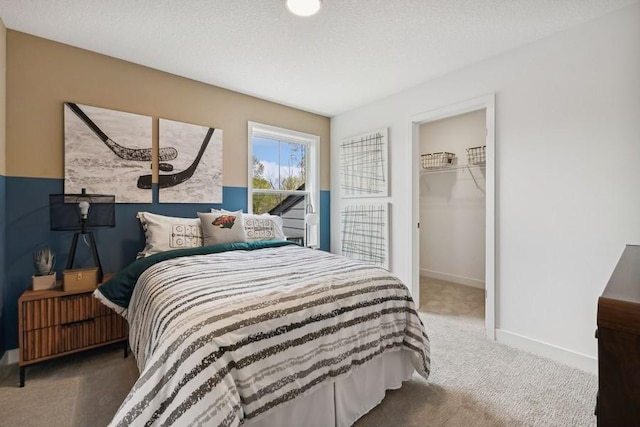 bedroom featuring carpet, a spacious closet, a textured ceiling, and a closet