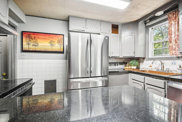 kitchen with white cabinets, sink, stainless steel appliances, and dark stone counters