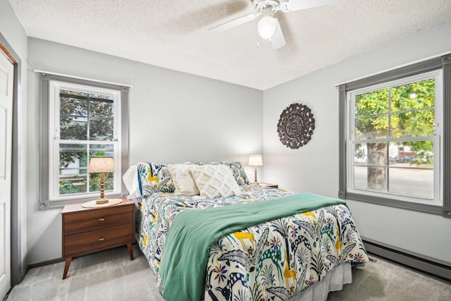 carpeted bedroom featuring ceiling fan, a textured ceiling, and a baseboard heating unit