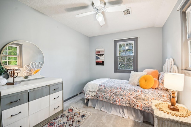 carpeted bedroom featuring multiple windows, a textured ceiling, and ceiling fan