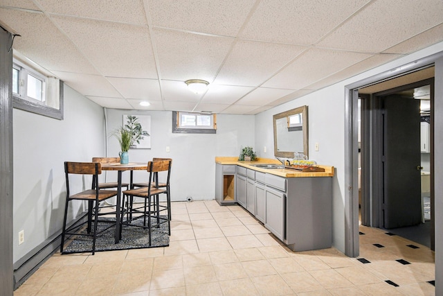 kitchen with light tile patterned flooring, gray cabinets, a drop ceiling, and sink