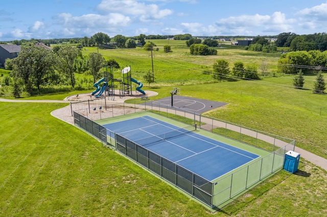 view of tennis court featuring a playground, basketball hoop, and a yard