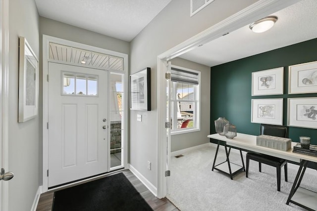 entrance foyer featuring hardwood / wood-style floors, a healthy amount of sunlight, and a textured ceiling