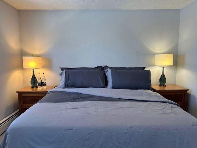 bedroom featuring a baseboard heating unit and a textured ceiling