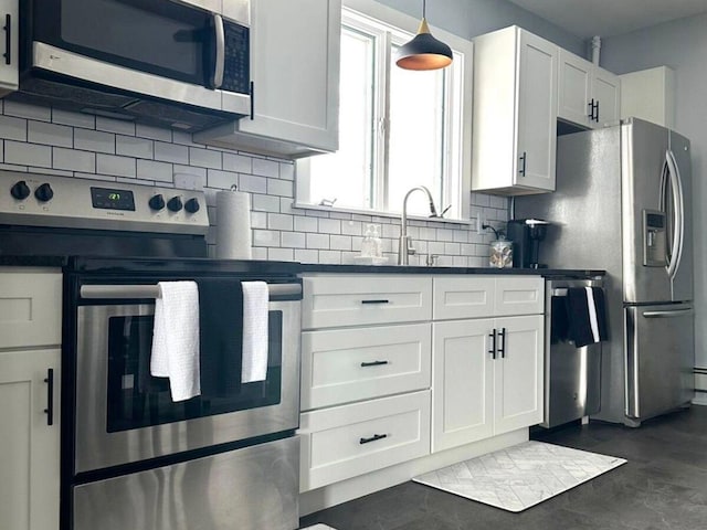 kitchen featuring stainless steel appliances, white cabinetry, backsplash, and decorative light fixtures