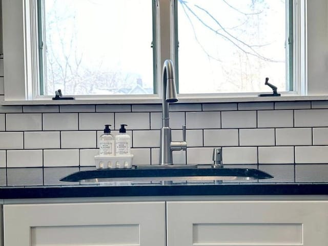 room details with white cabinetry, sink, and decorative backsplash