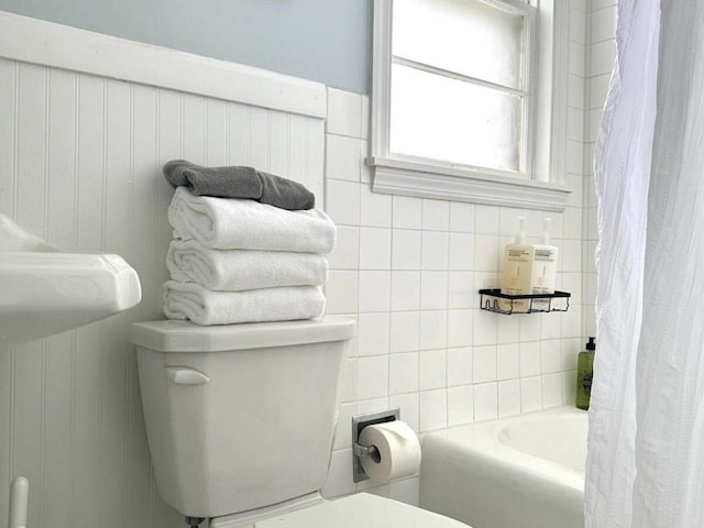 bathroom featuring shower / bathtub combination with curtain and toilet