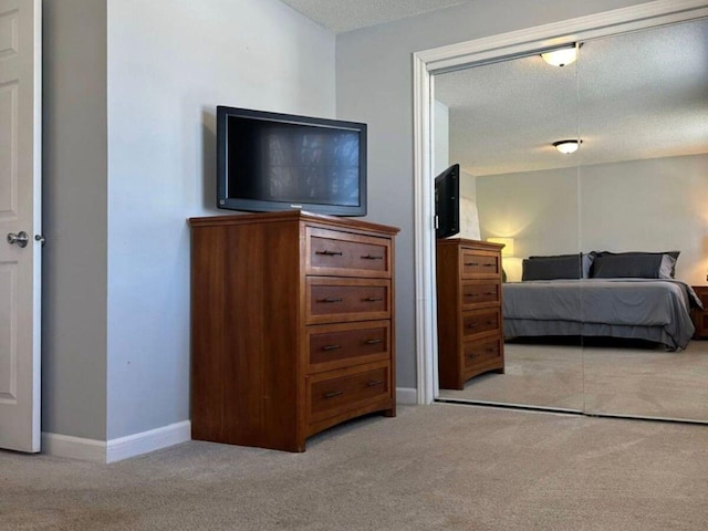 bedroom with light colored carpet, a closet, and a textured ceiling