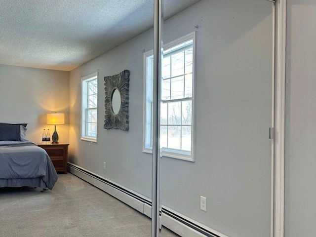 carpeted bedroom with a baseboard radiator and a textured ceiling