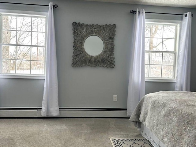 carpeted bedroom with a baseboard radiator, multiple windows, and a textured ceiling