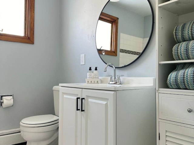 bathroom featuring vanity, a baseboard heating unit, a wealth of natural light, and toilet