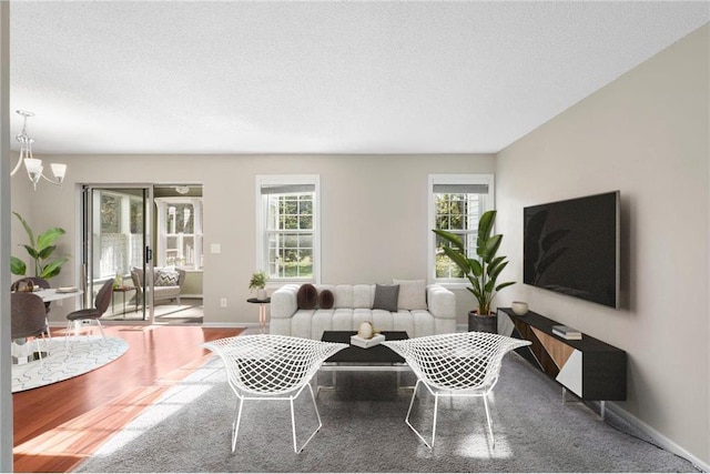 living room with wood-type flooring, a textured ceiling, a wealth of natural light, and a chandelier