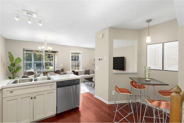 kitchen featuring dark hardwood / wood-style flooring, stainless steel dishwasher, sink, decorative light fixtures, and a notable chandelier