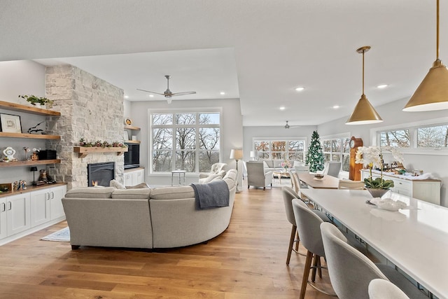 living room with ceiling fan, a fireplace, and light wood-type flooring