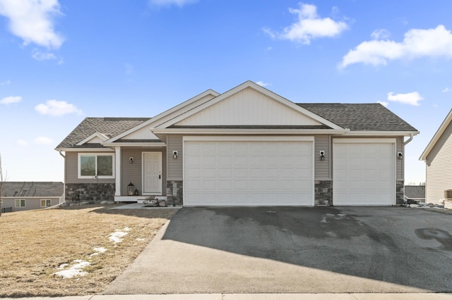 view of front facade featuring a garage, stone siding, roof with shingles, and driveway