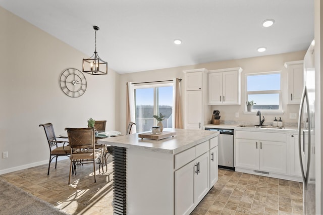 kitchen with stainless steel appliances, visible vents, a sink, a kitchen island, and plenty of natural light