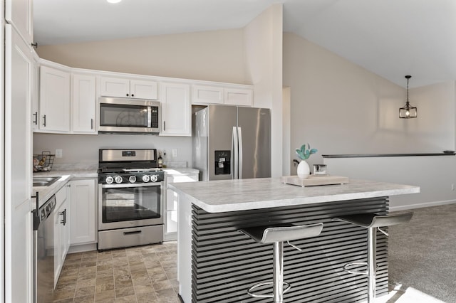 kitchen featuring stainless steel appliances, white cabinets, vaulted ceiling, light countertops, and decorative light fixtures