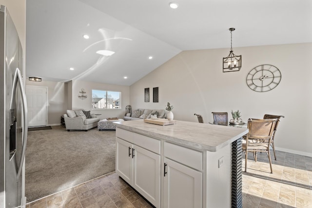 kitchen with carpet floors, open floor plan, white cabinets, vaulted ceiling, and stainless steel fridge