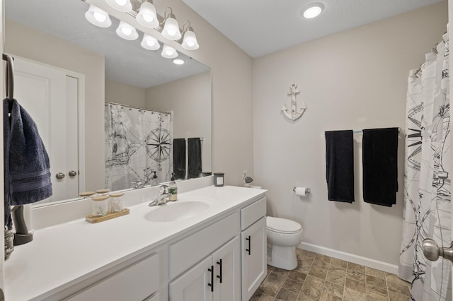 bathroom featuring toilet, vanity, and baseboards