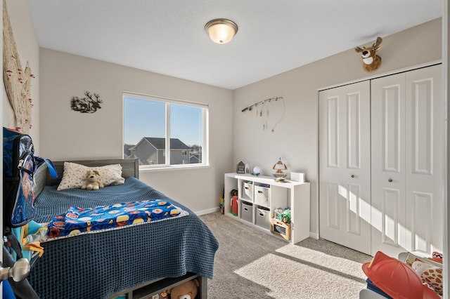 carpeted bedroom featuring baseboards and a closet